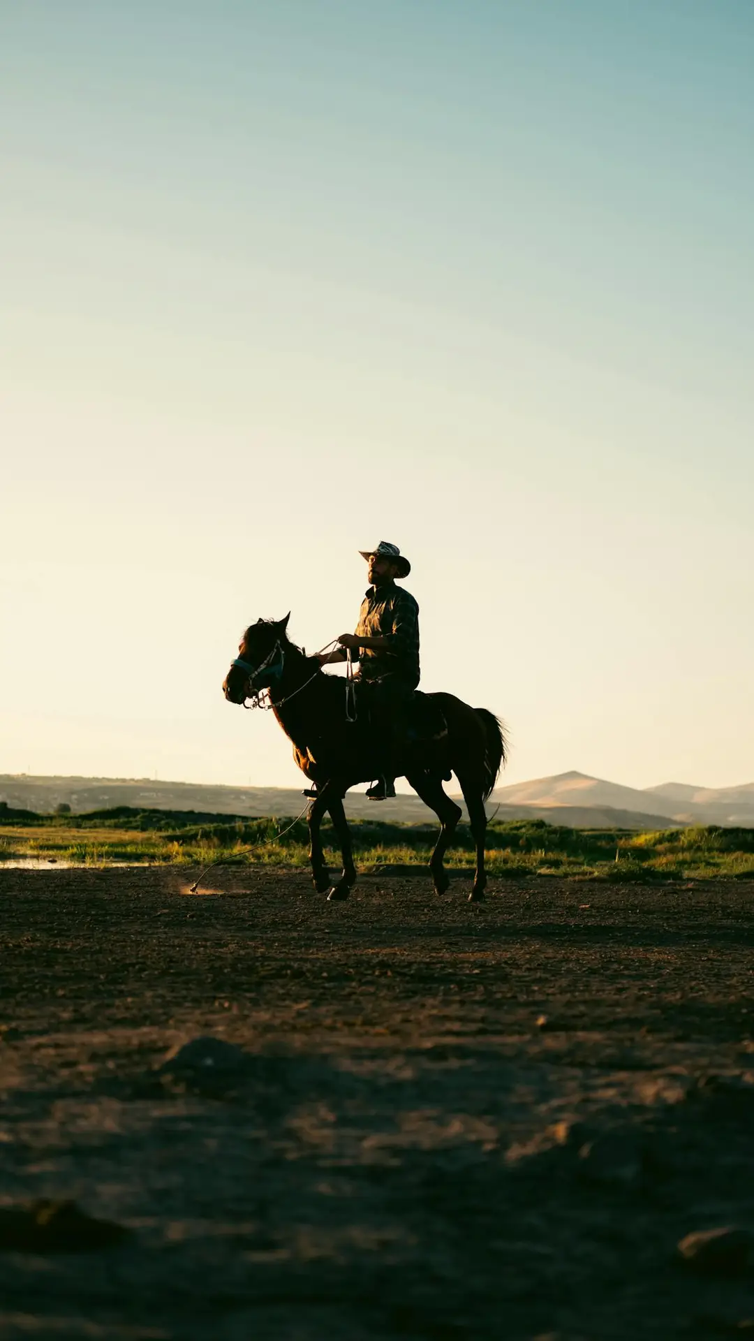 Silhouette of a cowboy on horseback at twilight in the open fields of Kayseri, Türkiye.